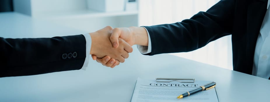 Two business executive shake hand in boardroom, sealing agreement merging two company. Handshake symbolize business partnership and cooperation. Corporate acquisition and merger concept. Shrewd