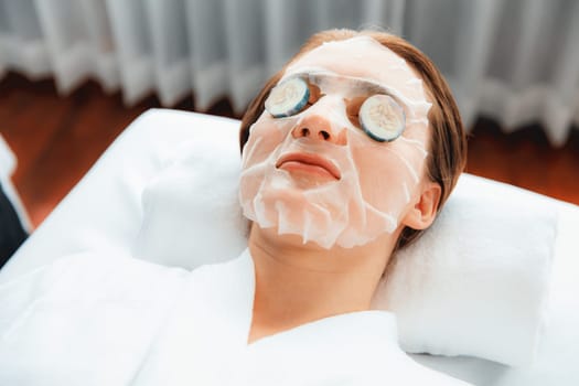 Serene daylight ambiance of spa salon, woman customer indulges in rejuvenating with luxurious cucumber facial mask. Facial skincare treatment and beauty care concept. Quiescent