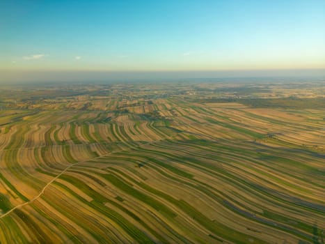 Drone view of endless agricultural landscape with road through fields under blue sky, Suloszowa village in Krakow County, Poland