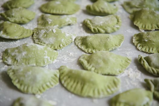 Food background with molded raw dumplings. Varennyky and ravioli on a floured marble surface of kitchen table. Ukrainian traditional cuisine. Food. Traditions and culture. Close-up