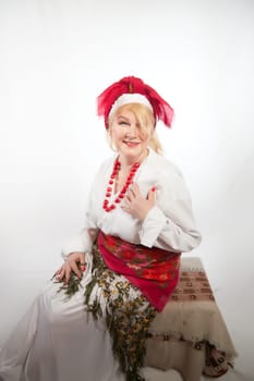 Portrait of cheerful funny adult mature woman solokha. Female model in clothes of national ethnic Slavic style. A stylized Ukrainian, Belarusian or Russian woman poses in a comic photo shoot