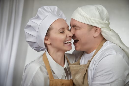 Cute oriental family with wife and husband cooking in kitchen on Ramadan, Kurban-Bairam, Eid al-Adha. Funny couple of cooks at joke photo shoot. Easter