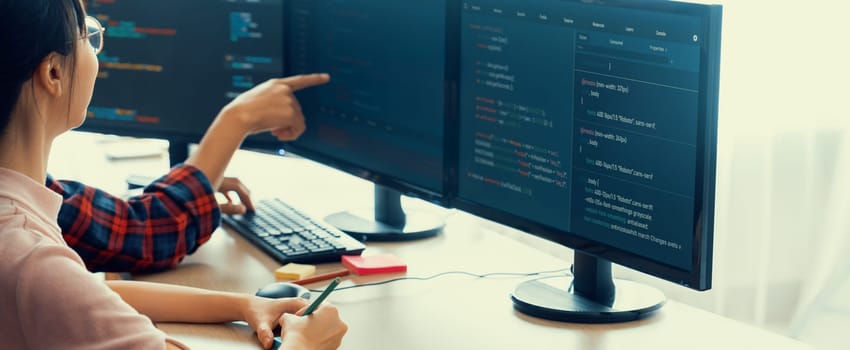 Female programer explain while pointing code displayed on computer. Professional programmer present data analysis and writing java script at modern company office. Closeup. Burgeoning.