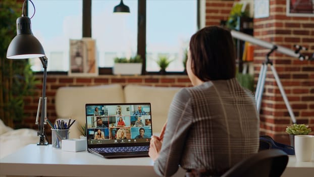 Remote employee in stylish apartment talking with coworkers during teleconference meeting. Teleworker at home participating in internet videocall with colleagues, camera B