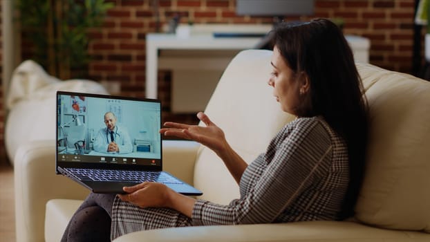 Patient sitting on couch, receiving treatment plan from medic during online videocall meeting after medical checkup. Indian person receiving prescription from GP in telemedicine call, camera B