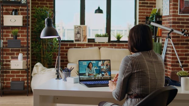 Teleworking team leader in cozy apartment discussing with coworkers during videoconference meeting. Company manager at home holding online videocall with workers, camera A
