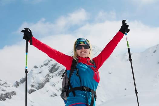 A professional woman skier rejoices after successfully climbing the snowy peaks of the Alps.