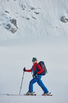 A determined skier scales a snow-capped peak in the Alps, carrying backcountry gear for an epic descent