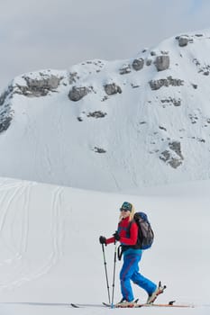 A determined skier scales a snow-capped peak in the Alps, carrying backcountry gear for an epic descent