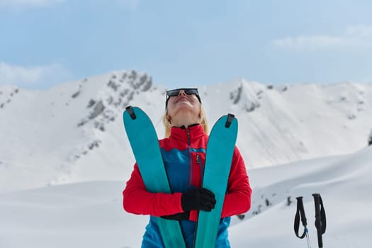 A professional woman skier rejoices after successfully climbing the snowy peaks of the Alps.