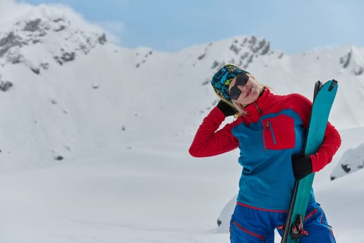 A professional woman skier rejoices after successfully climbing the snowy peaks of the Alps.