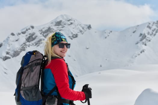 A determined skier scales a snow-capped peak in the Alps, carrying backcountry gear for an epic descent