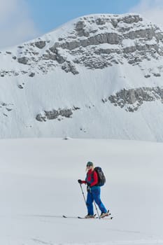 A determined skier scales a snow-capped peak in the Alps, carrying backcountry gear for an epic descent