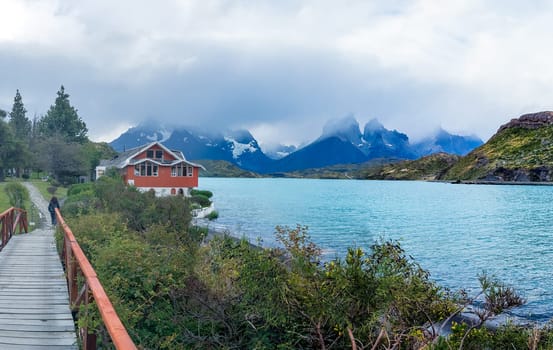 A striking red house by a turquoise lake with misty mountains.