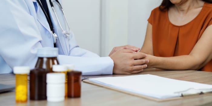 Doctor give hope. young female doctor hold the hand of elderly female patient to comfort her during medical consultation.