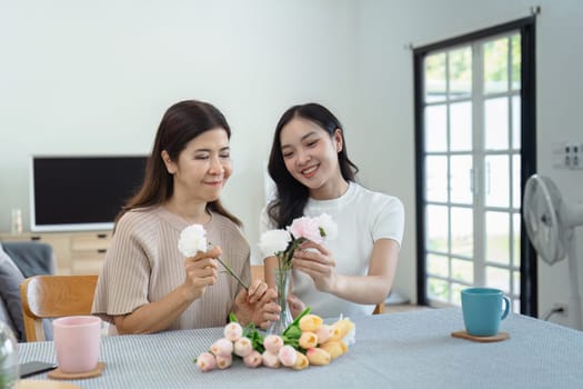 Mother and child arrange flowers together at home on the weekend, family activities, mother and daughter do activities together on Mother's Day.