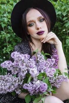 A fashionable girl with dark hair, a spring portrait in lilac tones in summer. Bright professional makeup