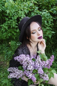 A fashionable girl with dark hair, a spring portrait in lilac tones in summer. Bright professional makeup