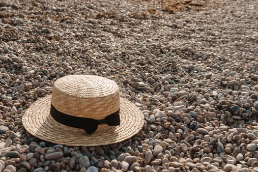 A straw hat on the beach. Pebbles on the seashore, close-up. The natural background.
