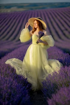 Lavender sunset girl. A laughing girl in a blue dress with flowing hair in a hat walks through a lilac field, holds a bouquet of lavender in her hands