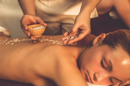 Closeup couple customer having exfoliation treatment in luxury spa salon with warmth candle light ambient. Salt scrub beauty treatment in Health spa body scrub. Quiescent