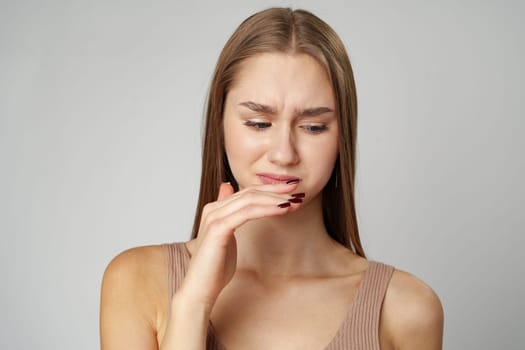 Beautiful young woman suffering from terrible teeth pain over gray background close up