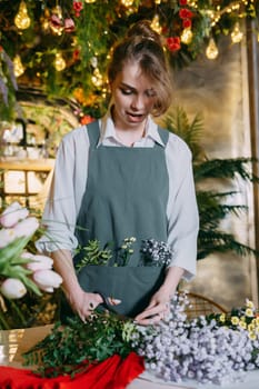 A woman in her florist shop collects bouquets of flowers. The concept of a small business. Bouquets of tulips for the holiday on March 8