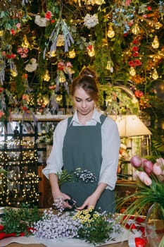 A woman in her florist shop collects bouquets of flowers. The concept of a small business. Bouquets of tulips for the holiday on March 8