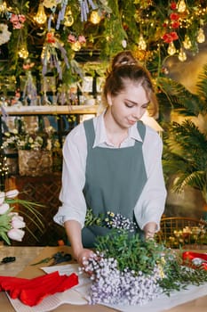 A woman in her florist shop collects bouquets of flowers. The concept of a small business. Bouquets of tulips for the holiday on March 8