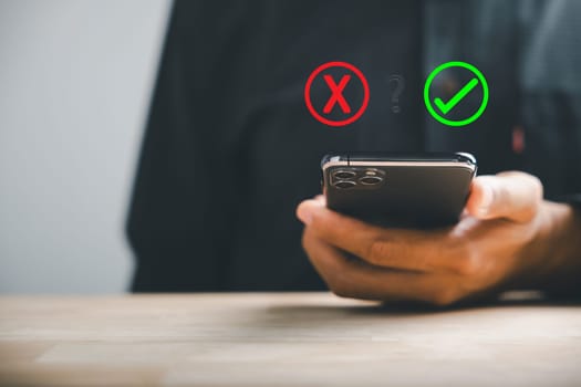 Businessman operates smartphones to exhibit right and wrong icons for yes or no decision-making. Communication of choice and success. Think With Yes Or No Choice.