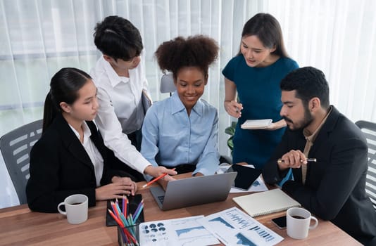 Multiracial analyst team use BI dashboard data to analyze financial report on meeting table. Group of diverse business people utilize data analysis by FIntech for success business marketing. Concord