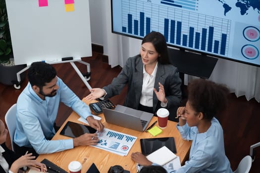 Top view multiracial analyst team use BI dashboard data to analyze financial report on meeting table. Group of diverse business people utilize data analysis by FIntech for business decision. Concord