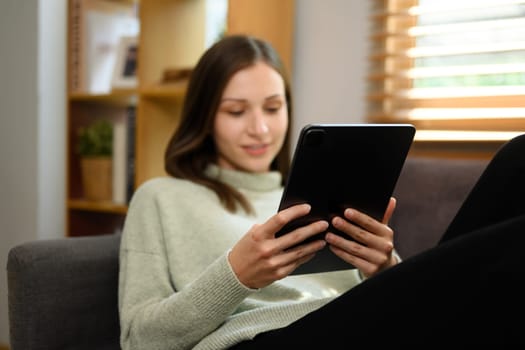 Carefree caucasian woman relaxing on couch and using digital tablet.