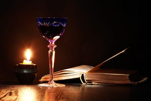 Nice vintage still life with wine glass near candle and old book