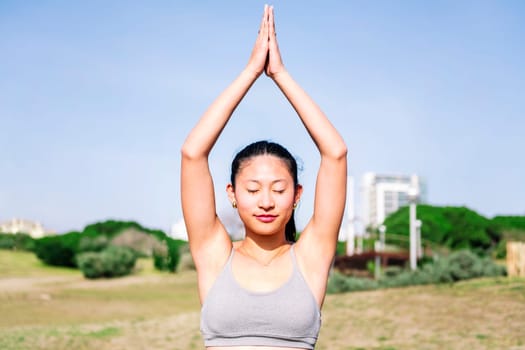 portrait of a young asian woman in sportswear doing yoga position at park, active and healthy lifestyle concept