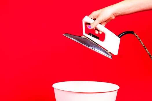 Woman putting iron in a recycle bin on red background