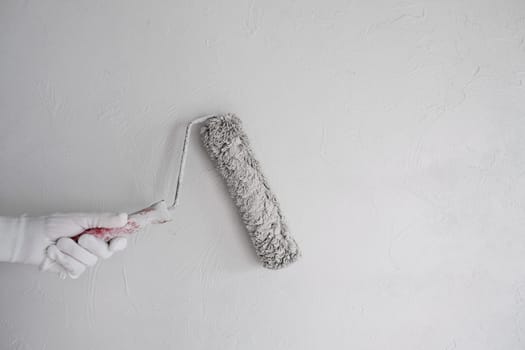 Painting the wall with a roller with white paint. Painting a bare wall with a roller with white paint. Apartment painting, renovation using white paint