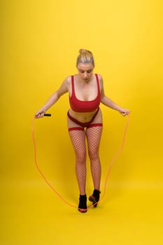 Beautiful fitness female posing in studio background with jumping rope
