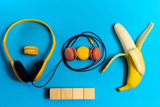 Minimalism flat lay concept, listens to a music. Headphones, banana on blue background. Top view