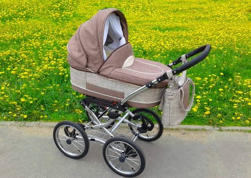 A brown cloth stroller for a newborn baby on a summer day