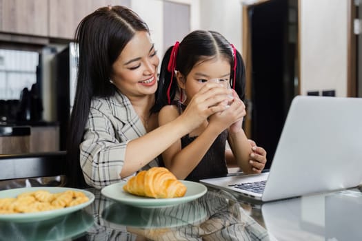 Business woman working at home. Businessman working on laptop and feeding child.