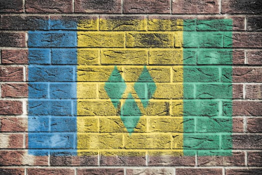 A Saint Vincent and The Grenadines flag on old brick wall background blue yellow green stripes diamonds