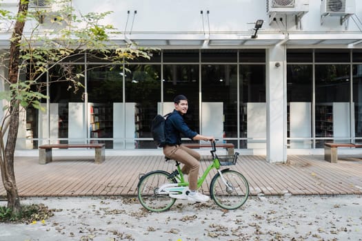 A man rides a bicycle down a sidewalk in front of a building with a lot of books. The man is wearing a backpack and a blue shirt. The scene is peaceful and calm, with the man enjoying his ride