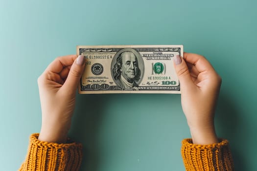 A person is holding a 100 green banknote in their hand, with their thumb and finger making a gesture. The currency is money cash
