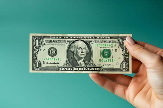 The person is holding a green banknote in their hand, using their thumb and finger to trace the intricate font of the currency. They seem to be handling the cash with care