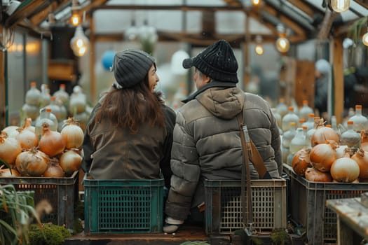 A couple is seated on a bench at a greenhouse, admiring onions. They are surrounded by the sights and smells of fresh, natural foods in a city marketplace
