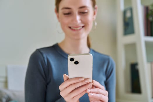 Close-up of smartphone in hands of young smiling woman. Happy teenage female using phone, texting, reading. Modern wireless technologies, Internet, online, mobile apps applications, digital gadgets