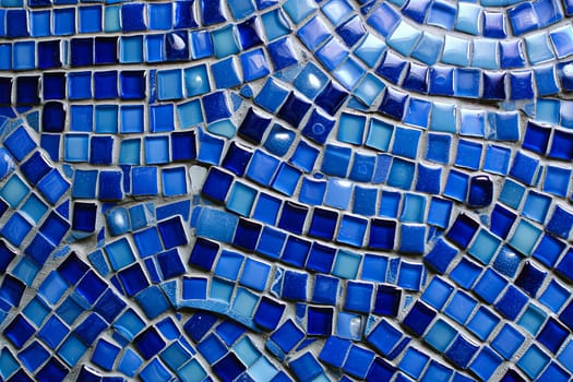 A blue mosaic tile wall with a blue and white swirl pattern. The tiles are blue and white and are arranged in a way that creates a sense of movement and depth