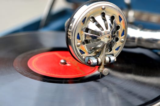 An old retro record playing on old vintage gramophone at flea market. Work of portable gramophone. Old vintage shabby record player, phonograph, potefone. Needle close up. Nostalgia antique turntable