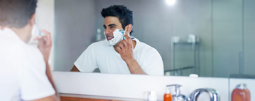 Shaving cream, mirror and man in bathroom for hygiene, grooming and washing face at home, house and apartment. Male person, gen z guy and reflection of student with foam, banner and skin care routine.